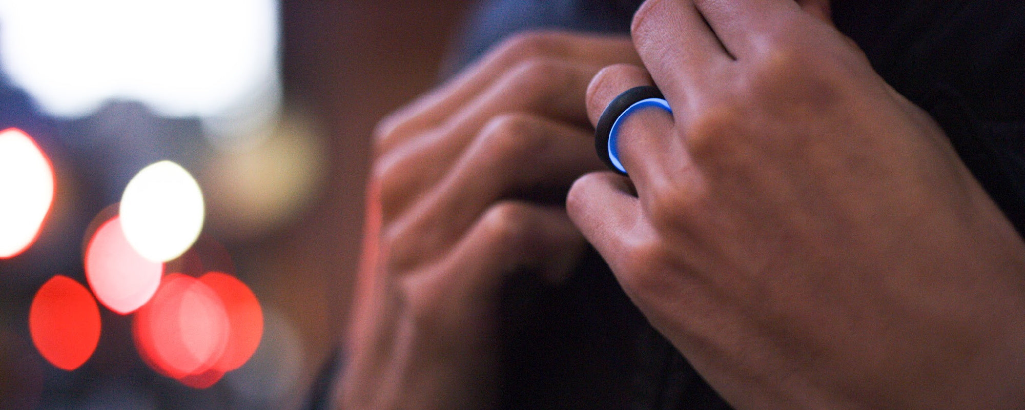 Forged carbon fiber ring with blue glow interior featured on a hand model. 