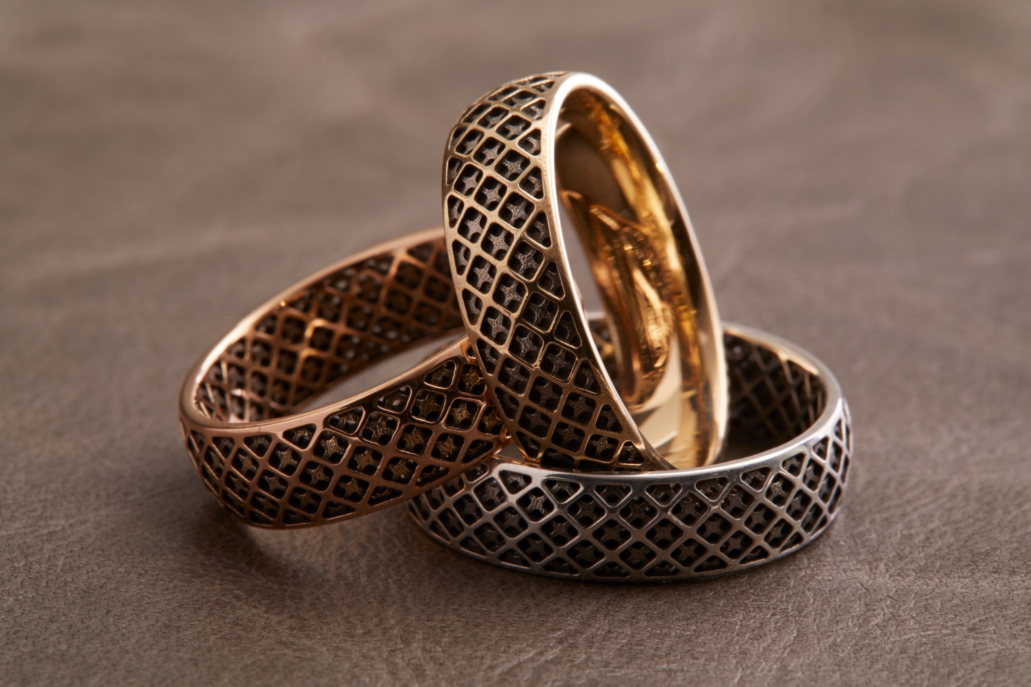 Three stacked gold rings featuring an interior and exterior square-based grid pattern.